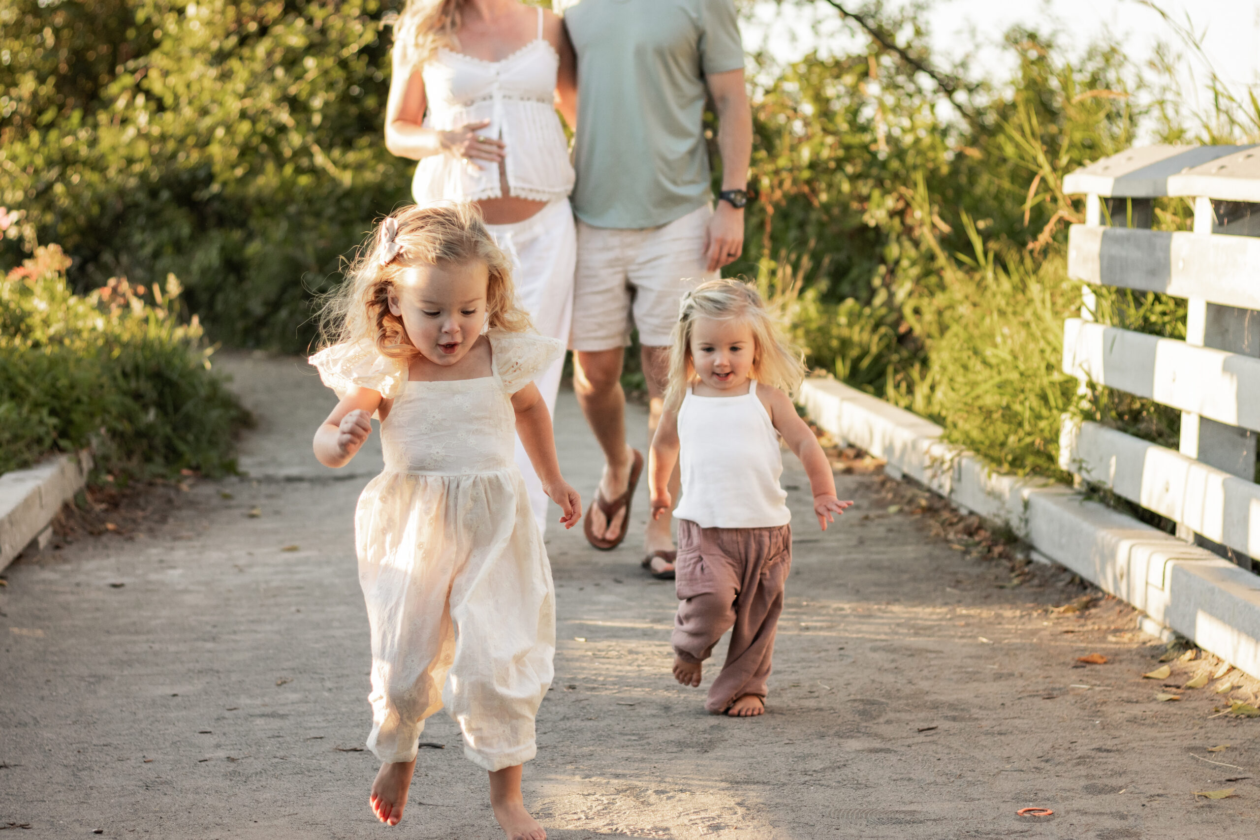 Pregnant Mom walking behind two girls running.