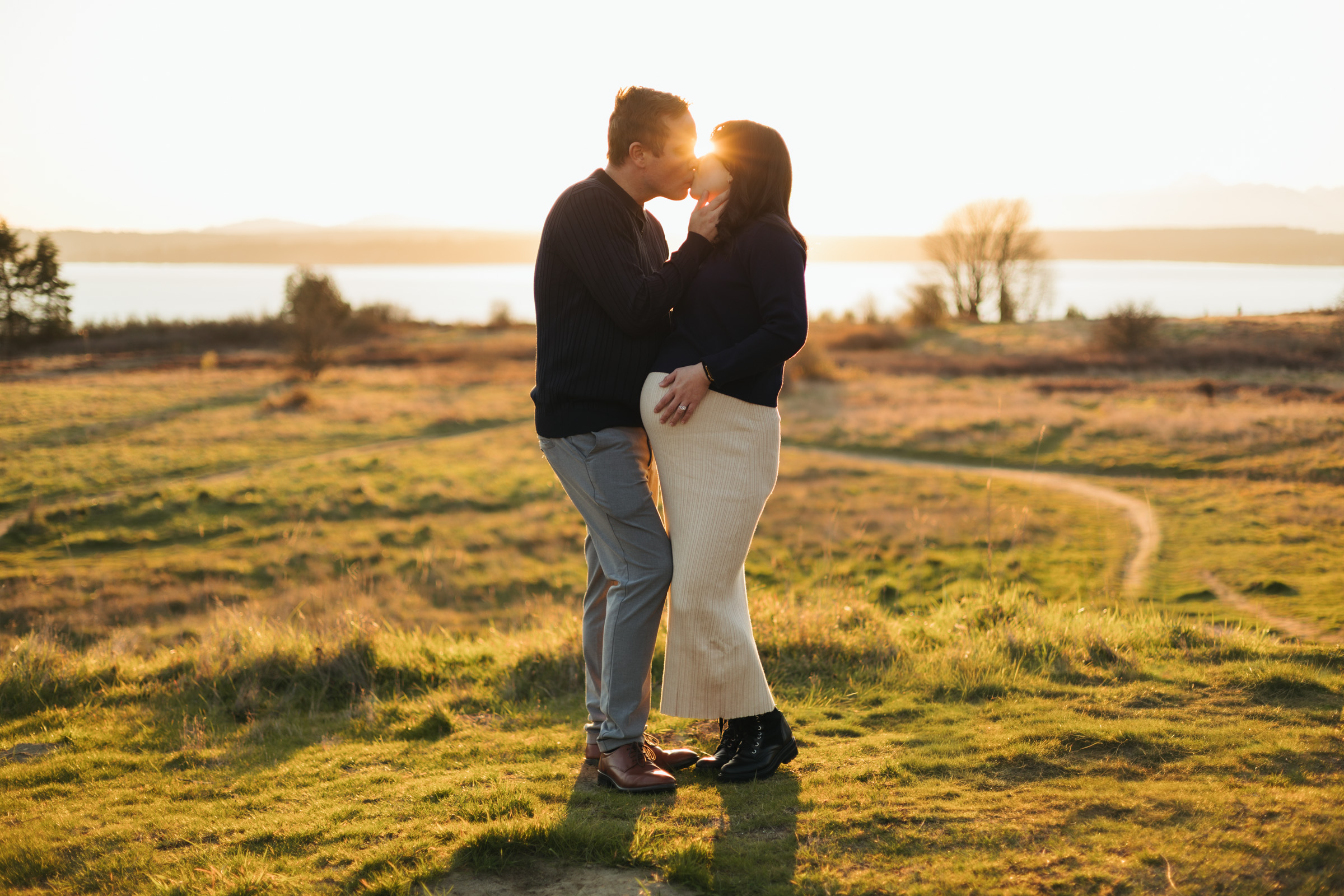 discovery park sunset pregnant couple kissing holding belly